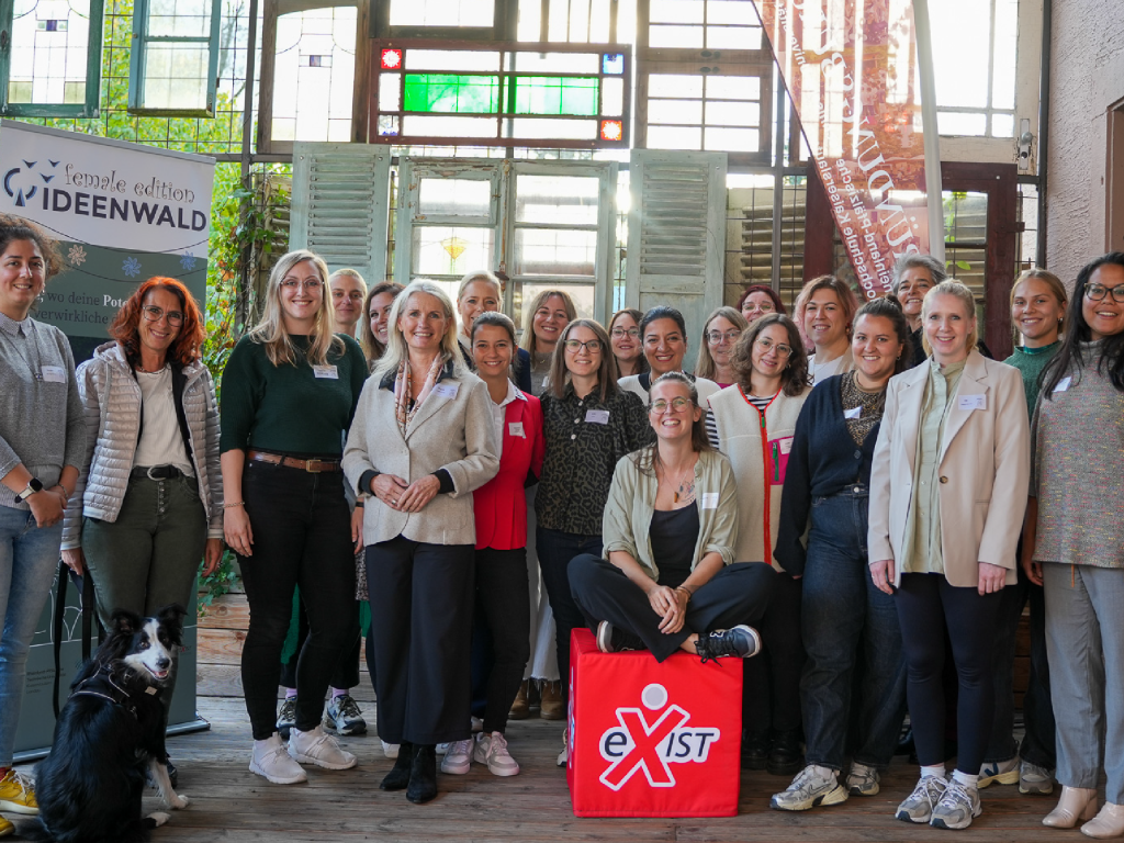 Gruppenfoto bei einer EXIST-Women Veranstaltung mit Banner „Ideenwald Female Edition“. Geben Sie Ihr Feedback zu BizChat ab.