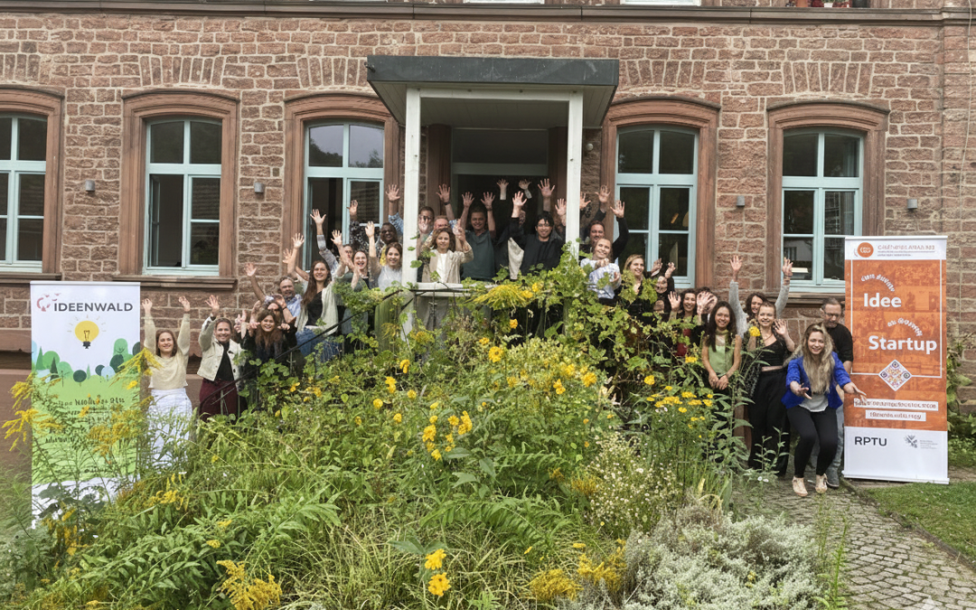 Gruppenfoto vor historischem Gebäude mit Bannern „Ideenwald“ und „Idee trifft Startup“.